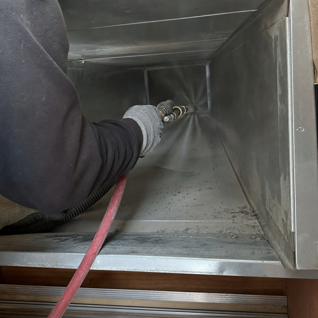 Professional technician cleaning residential HVAC air ducts with compressed air tools